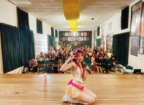 Lyv Marz junto a fotos suyas de fondo en un evento